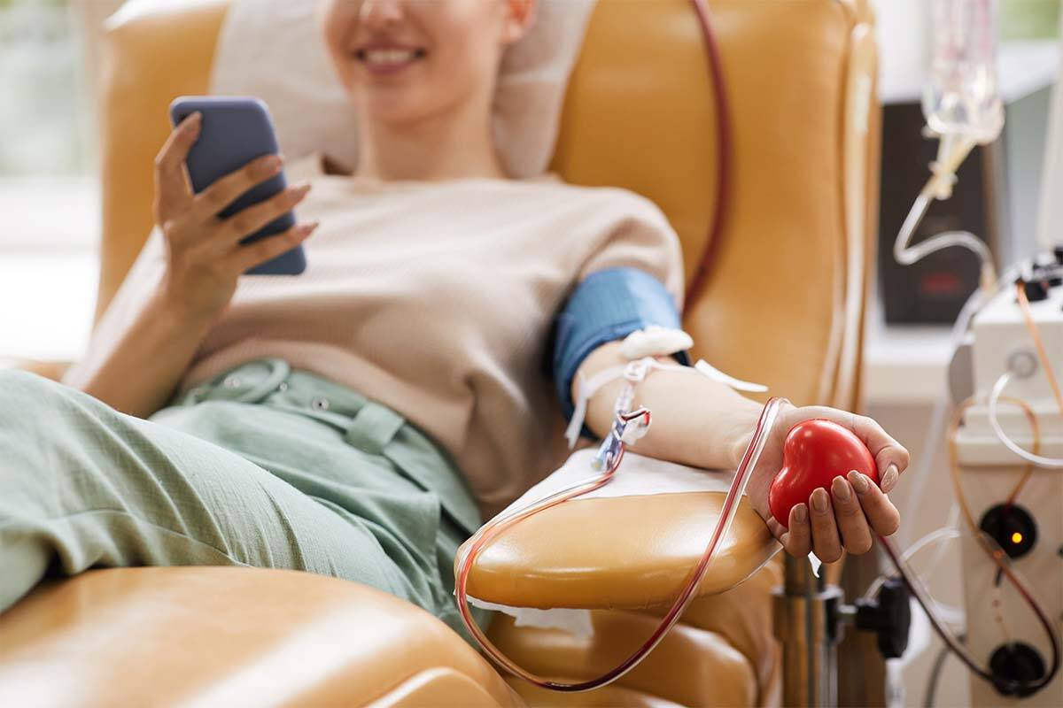 woman sitting in chair with needle in her arm donating blood