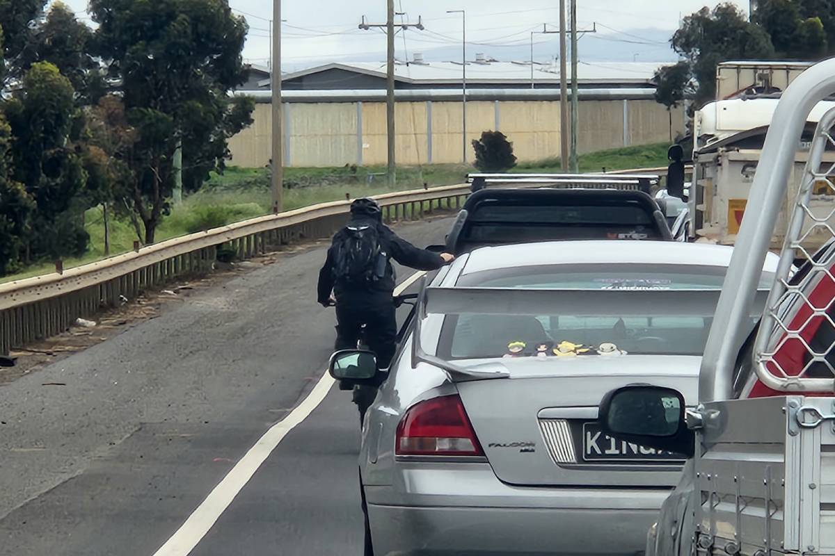 Article image for Bike rider grabs onto side of ute on Western Highway